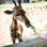 child in pink t-shirt and orange baseball cap feeding giraffe foliage at zoo