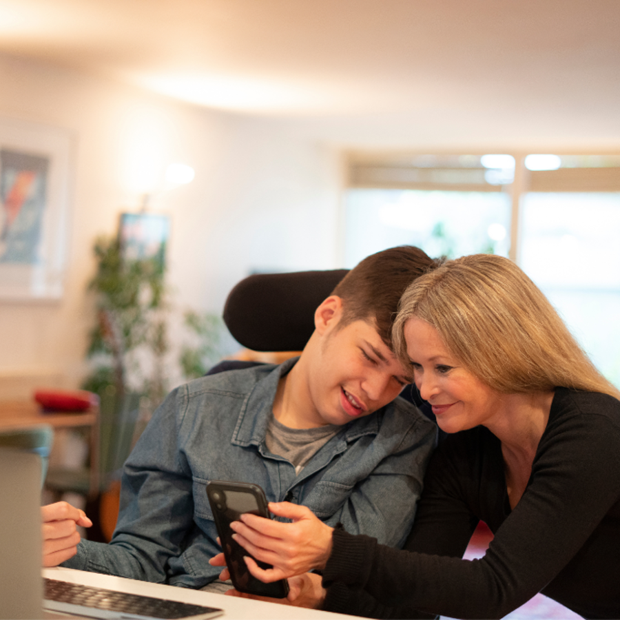 Disabled male young adult looking at phone with female adult
