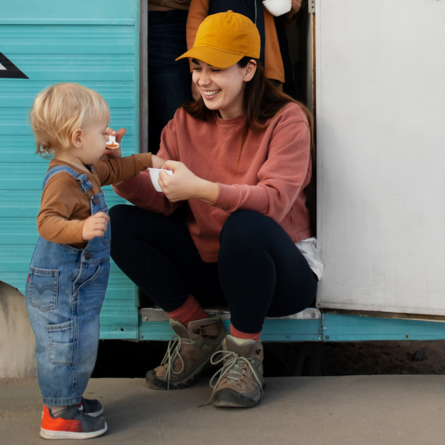 Woman Sitting On Ste Of Static Caravan Giving Drink To A Toddler