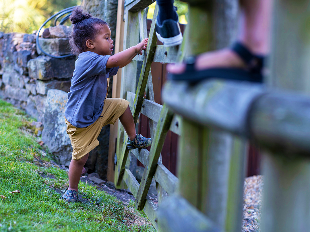 child climbing on a wooden gate during a walk outside
