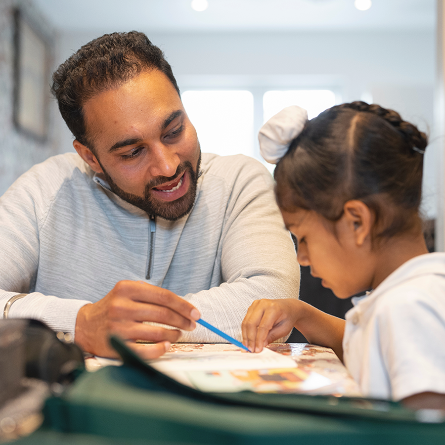 Man helping a child to learn from a book at home.