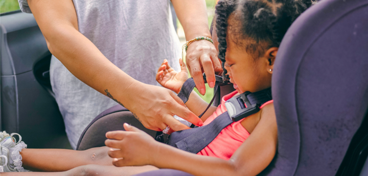 Child Being Clipped Into A Car Seat By Adult