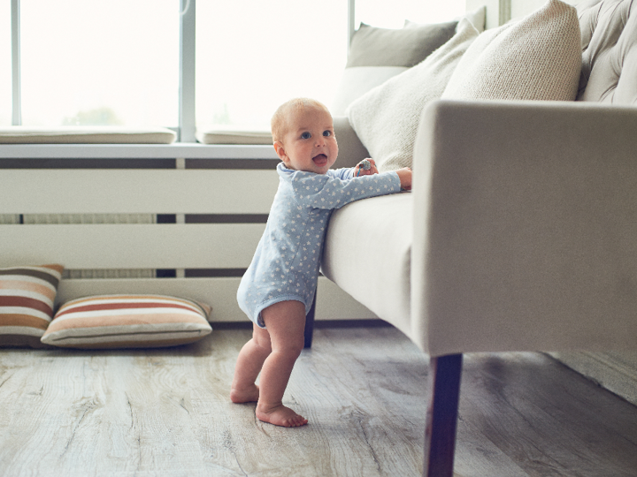 8 Month Old Baby Boy Standing Next To Sofa Holding On For Support