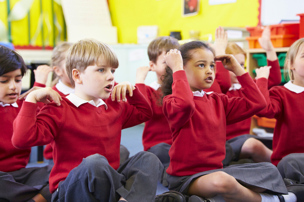 Children in classroom sitting and singing songs with actions